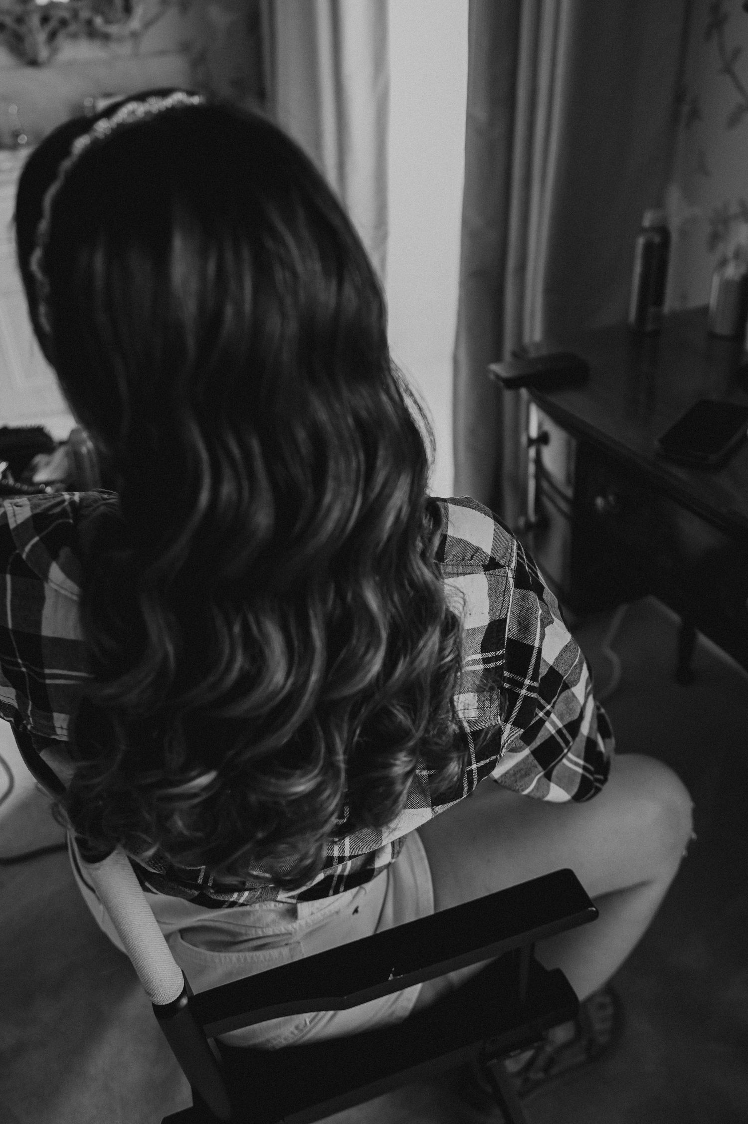 Back view of wavy dark hair styled for special occasion against vintage wallpaper.