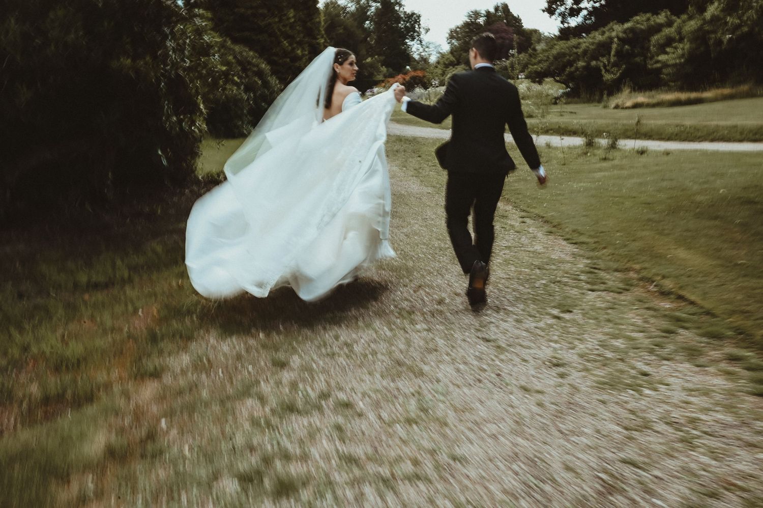 A couple walks down a garden path after their wedding ceremony.