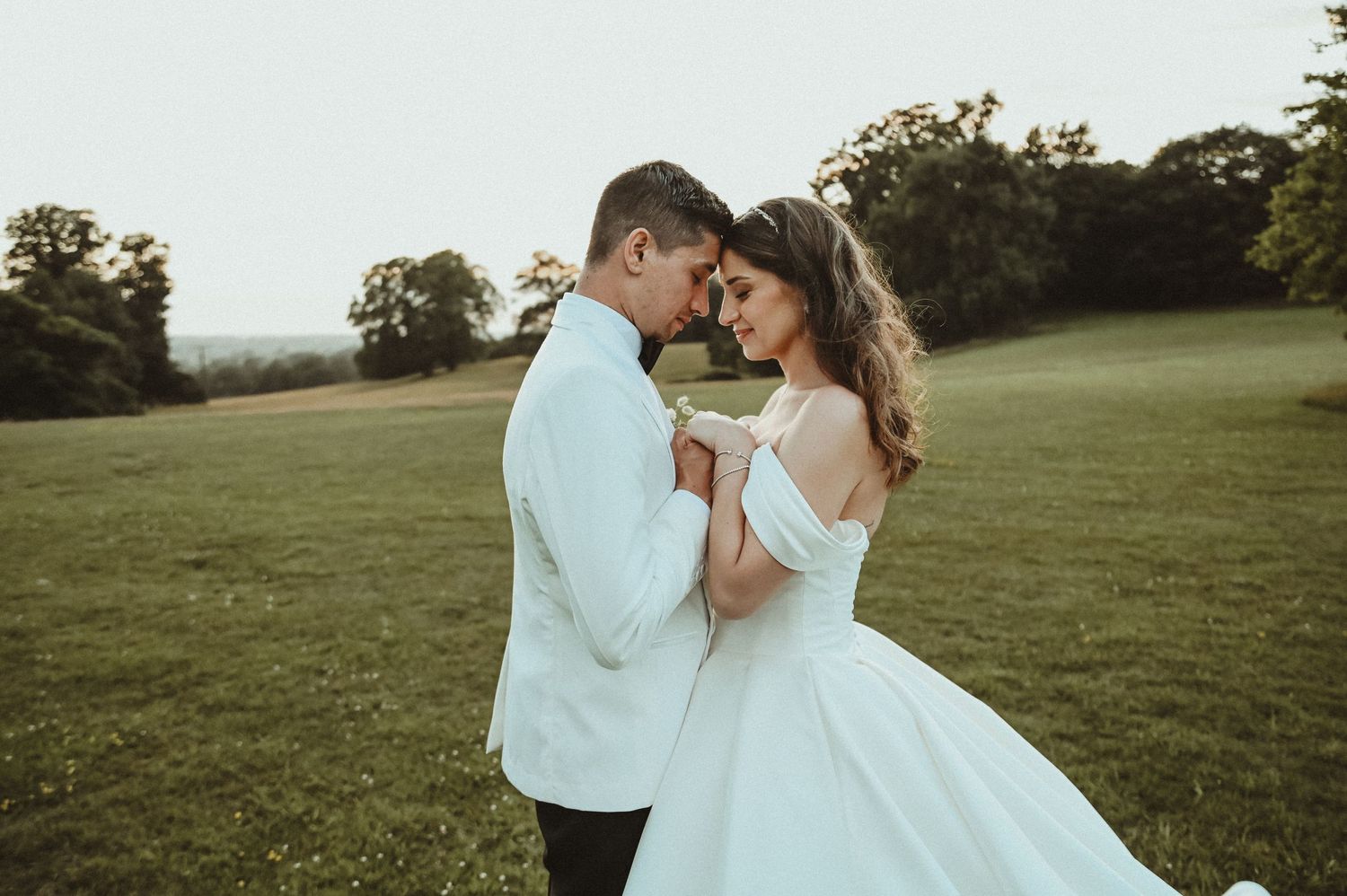 A romantic moment between a couple in wedding attire on a hilltop.
