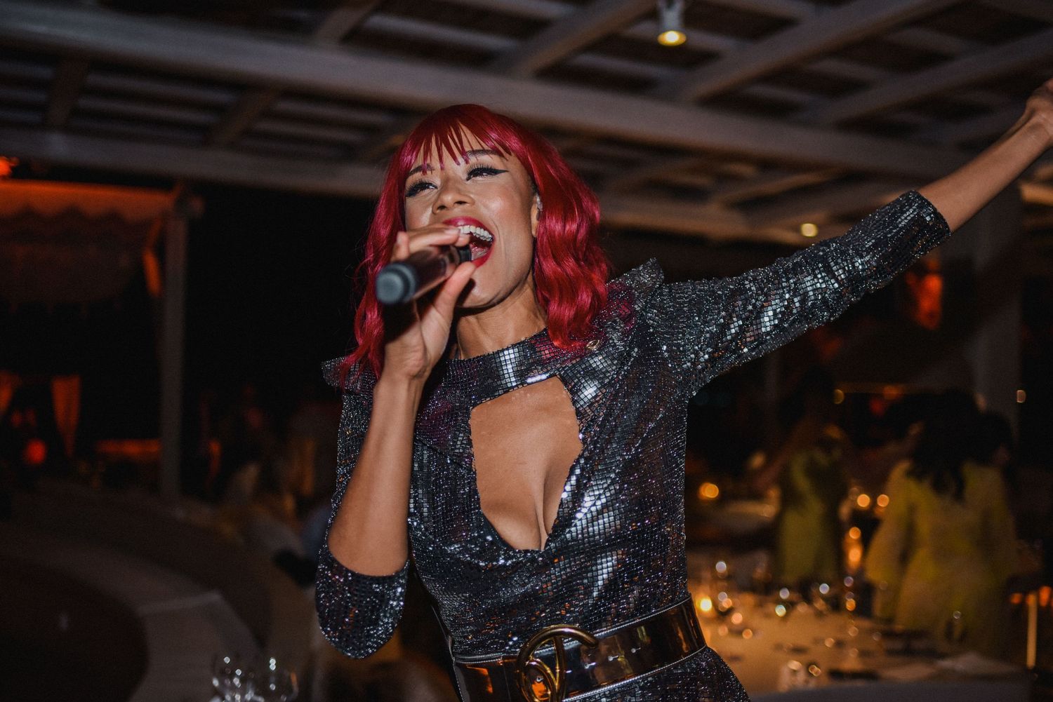 Performer in sparkly outfit sings passionately on stage during evening entertainment.