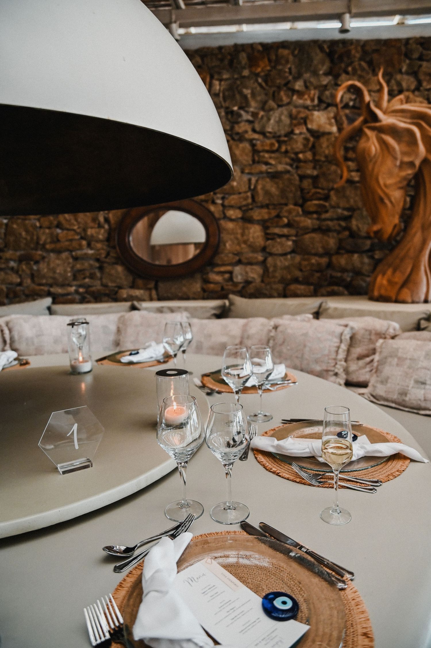 Modern restaurant table setting with dome light and stone wall backdrop.