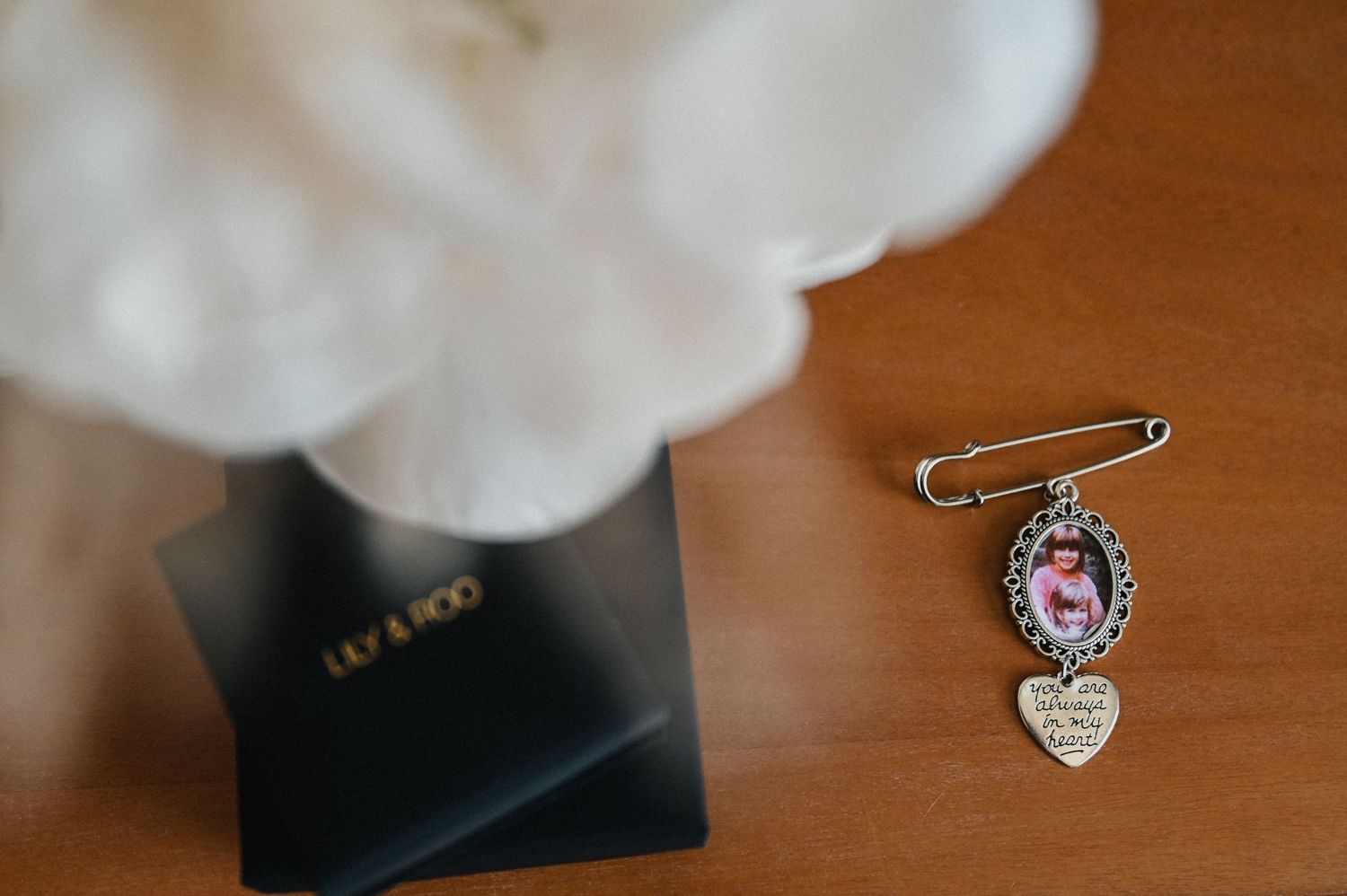 Vintage-style brooch pin with ornate details displayed on a wooden surface.