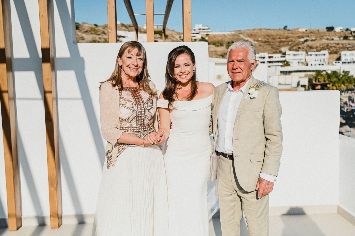 Wedding portrait on a sunny terrace overlooking coastal views.