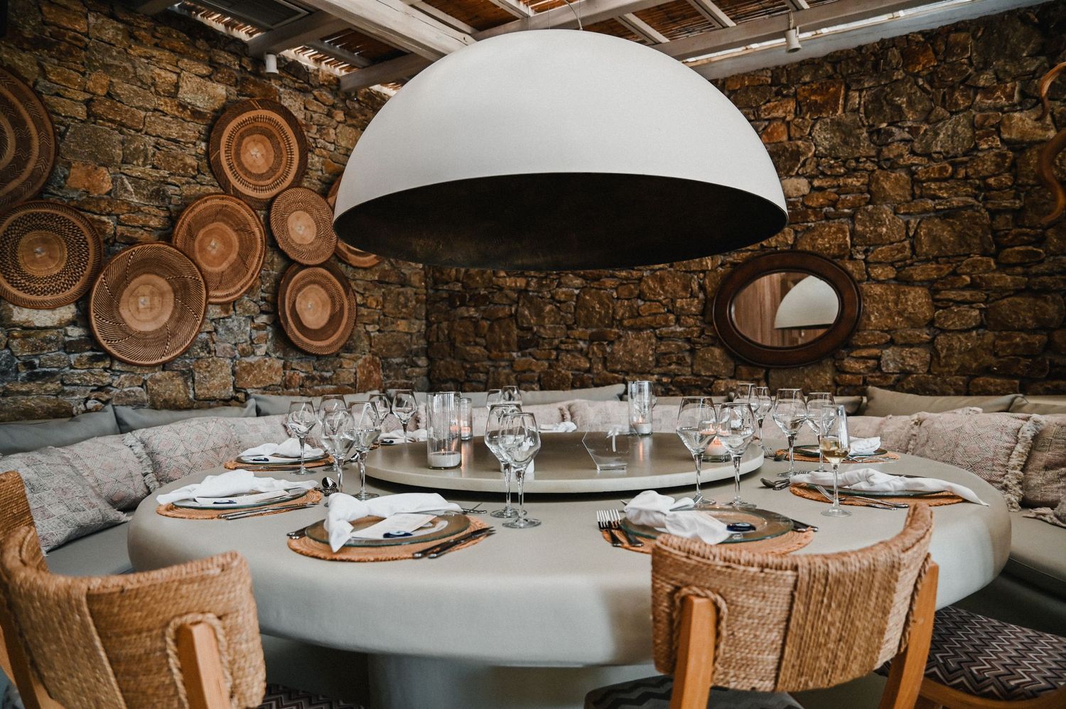 Modern restaurant interior with curved banquette seating and large dome pendant light.