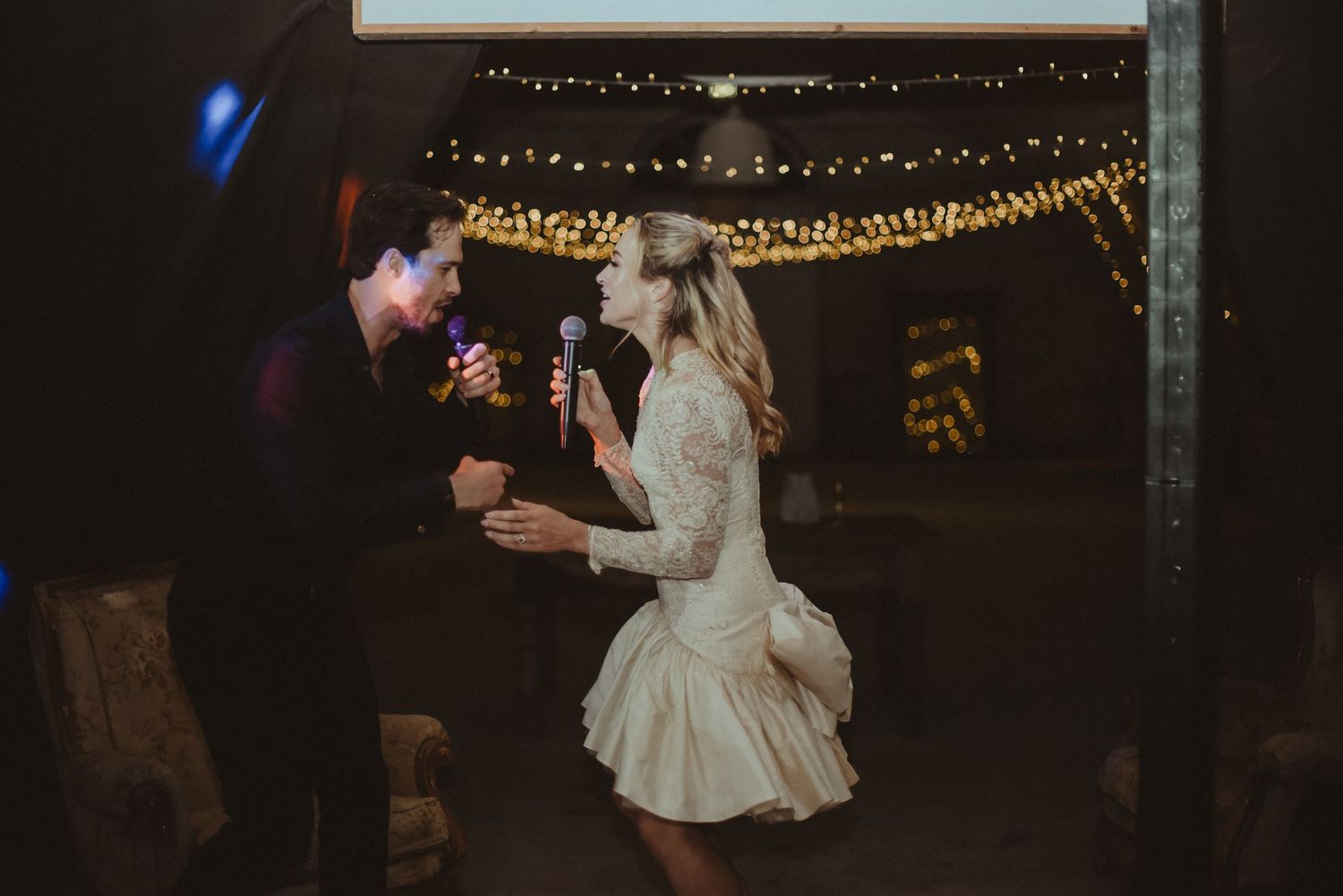 A couple sharing an intimate dance moment under warm string lights at their wedding celebration.