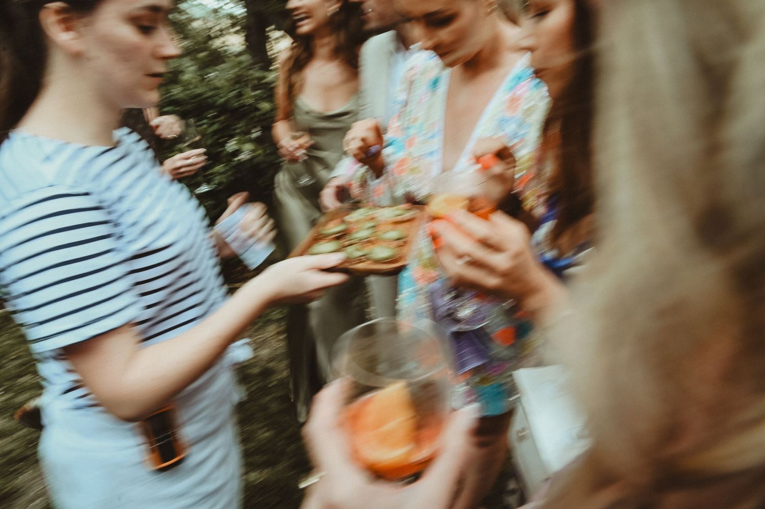 Blurred motion shot of guests enjoying food and drinks at casual outdoor gathering.
