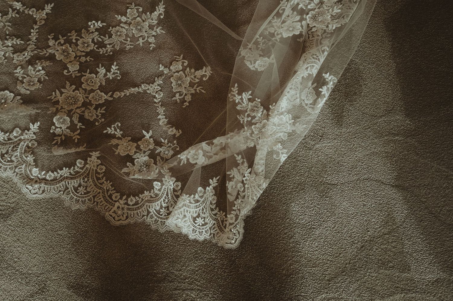 Close-up detail of intricate lace pattern on wedding veil fabric.