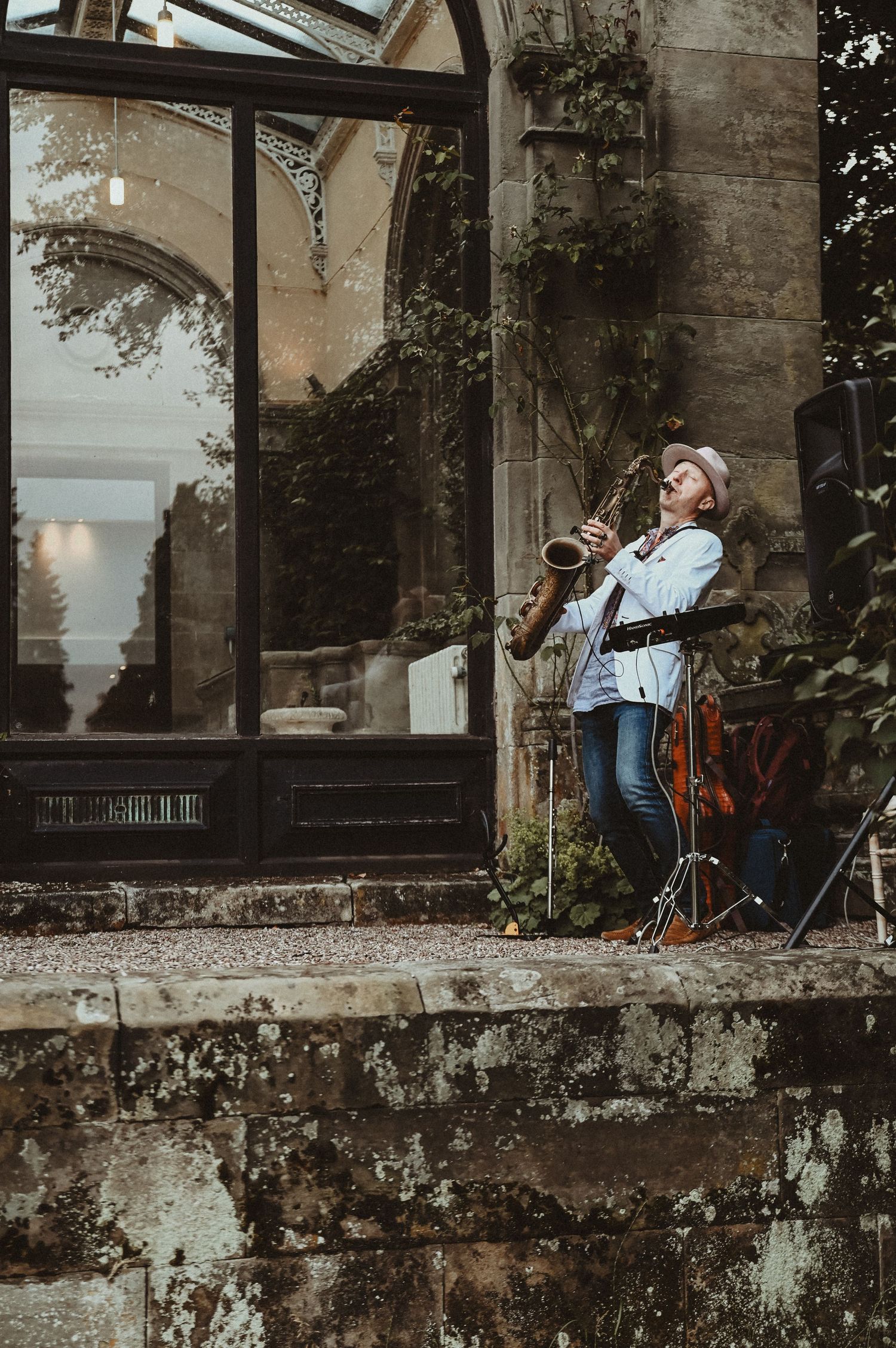 Musician performing on stone steps outside a historic building with arched windows.