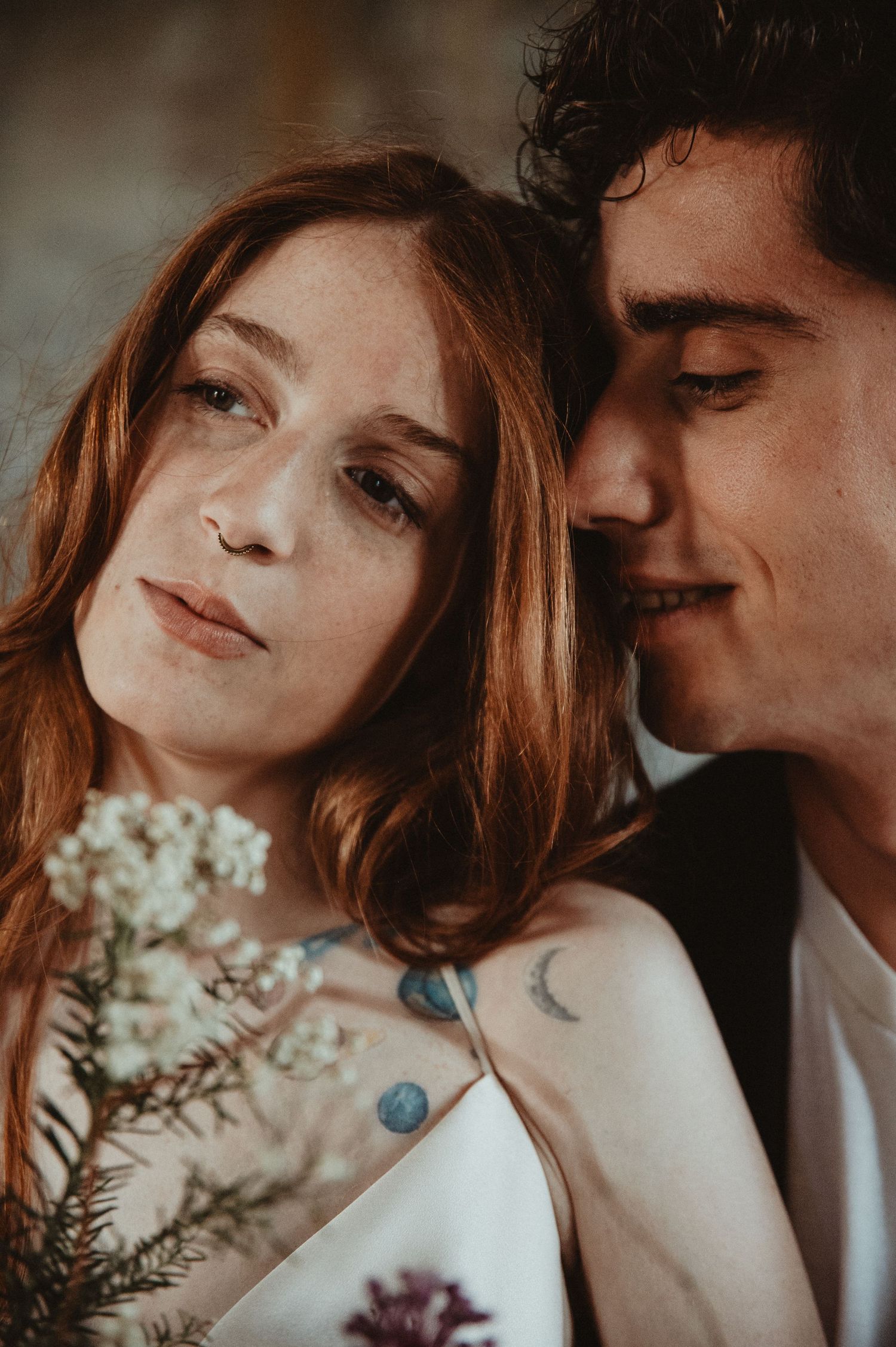 Romantic close-up portrait showing tender moment with natural flowers and soft lighting.