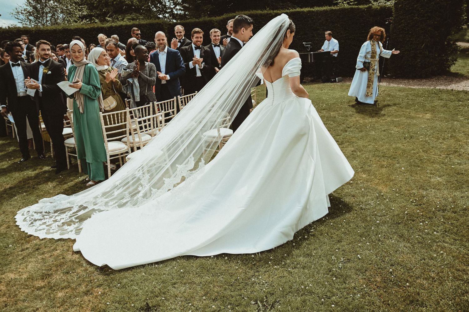 Stunning wedding gown with long flowing train captured during an outdoor ceremony.