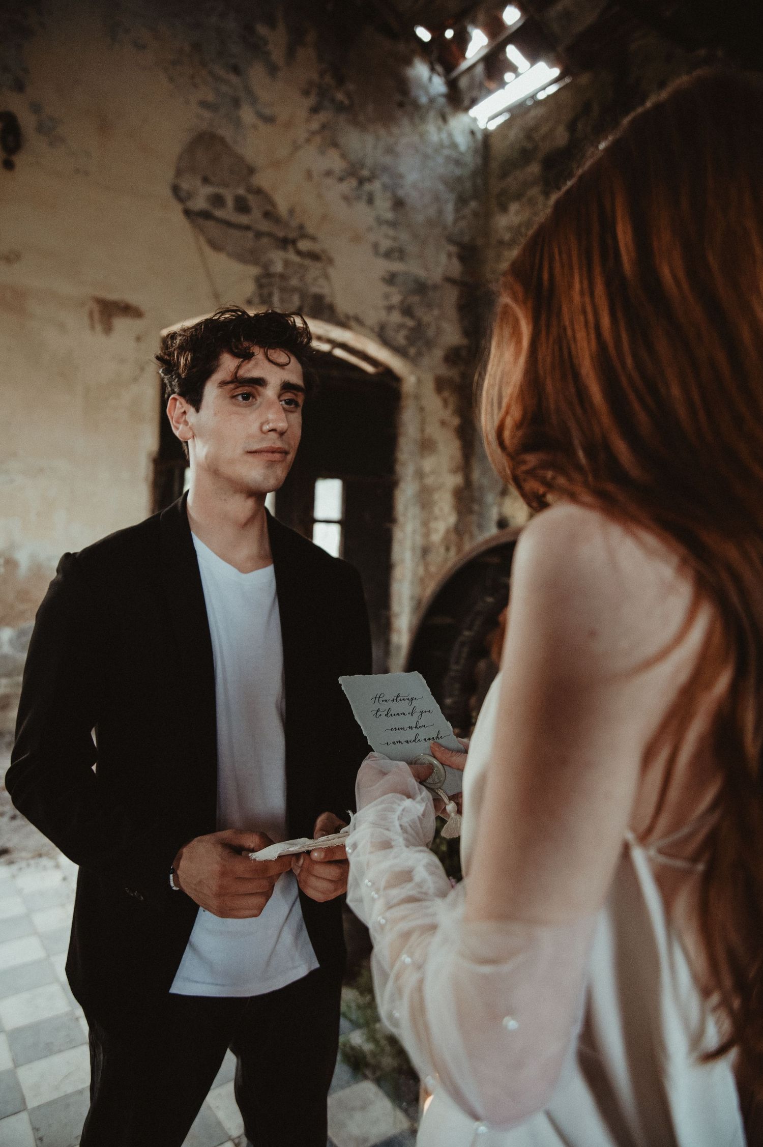 A wedding ceremony in a historic building with natural light streaming through windows.