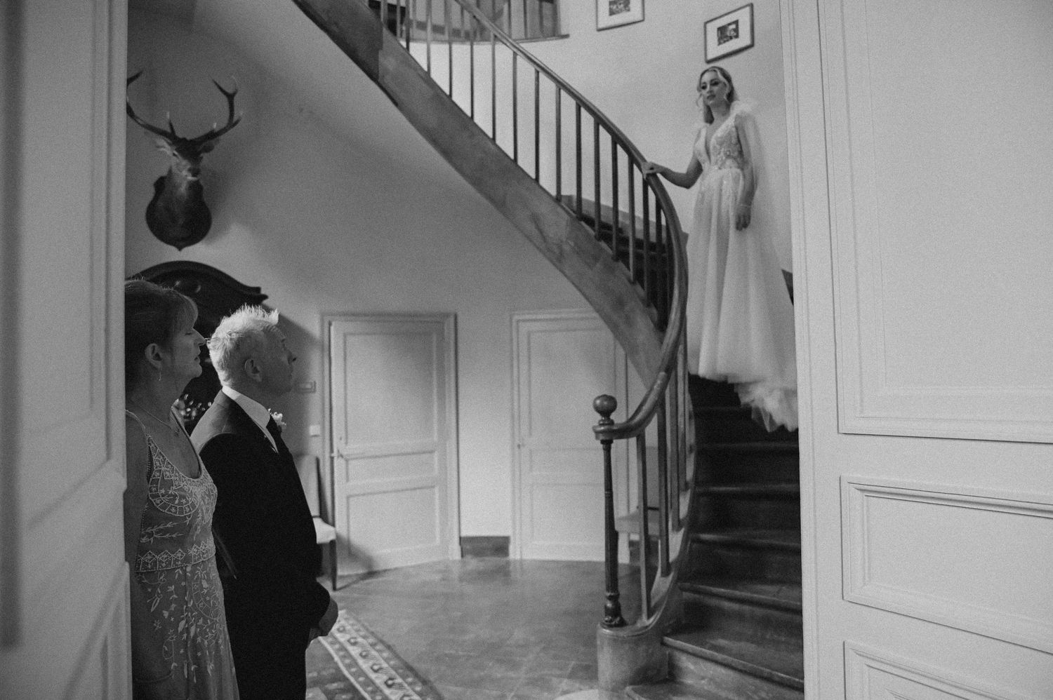 A vintage black and white photograph showing people gathered on an elegant staircase.