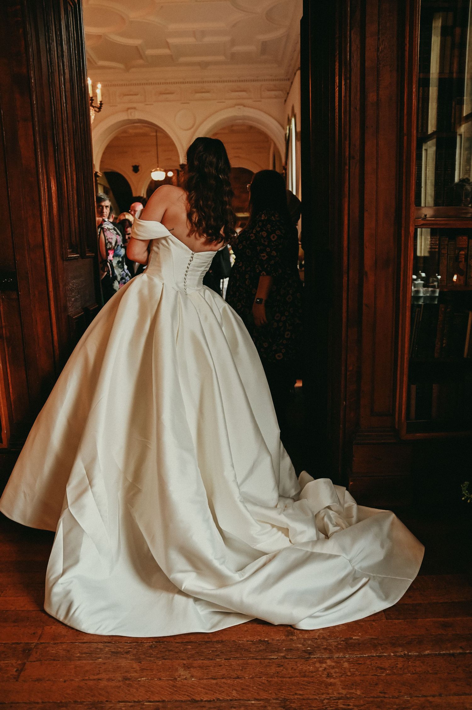 Back view of a stunning white ball gown wedding dress with a dramatic train in an ornate hallway.
