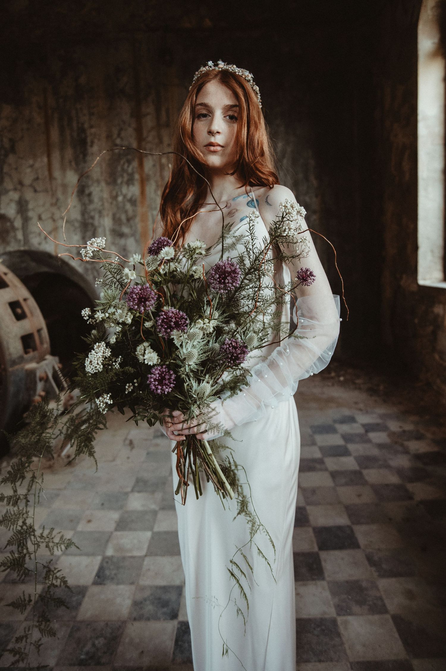 Ethereal bridal portrait with wildflower bouquet in a vintage setting.
