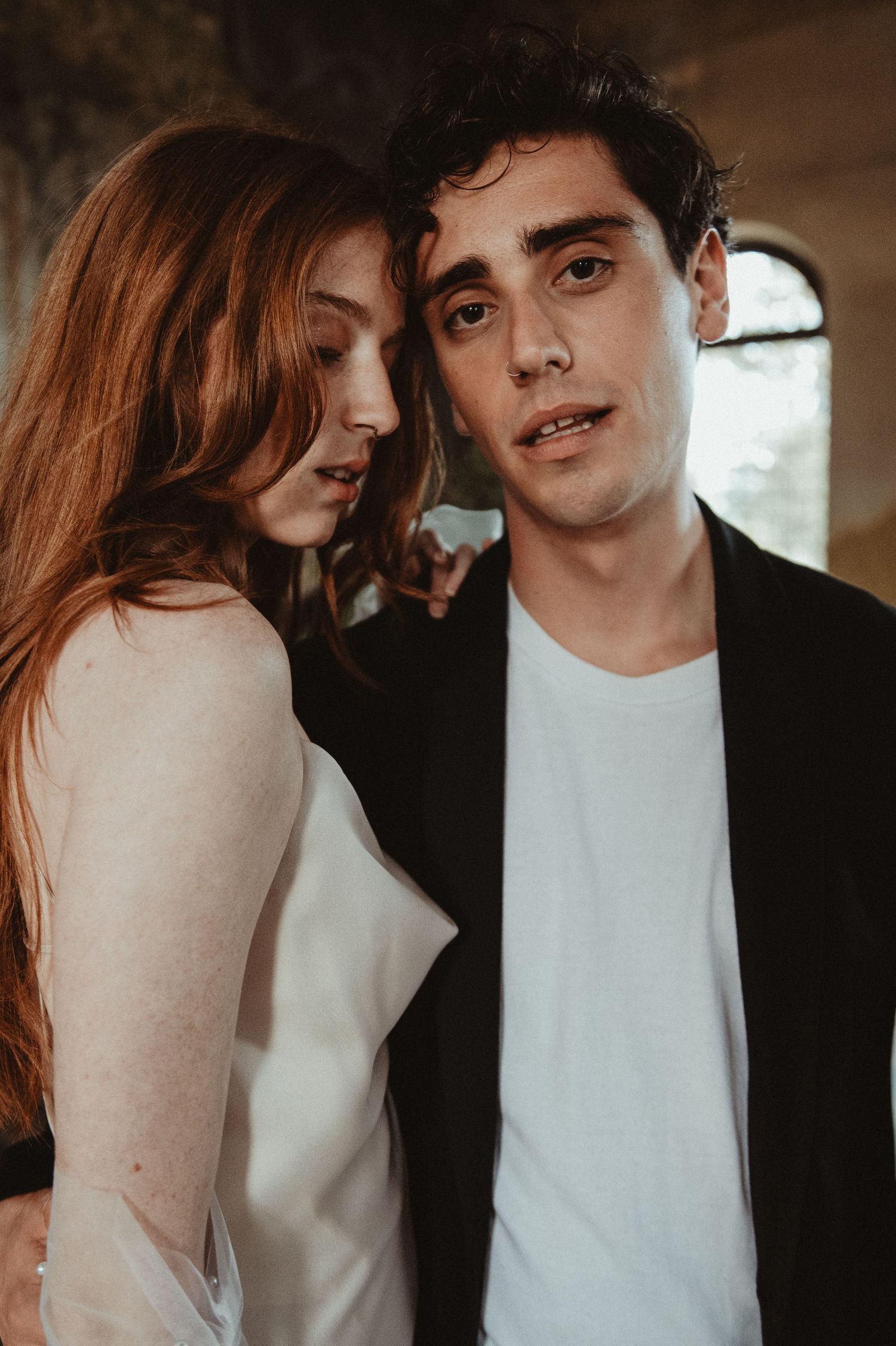 Natural light portrait capturing intimate moment against stone wall background.