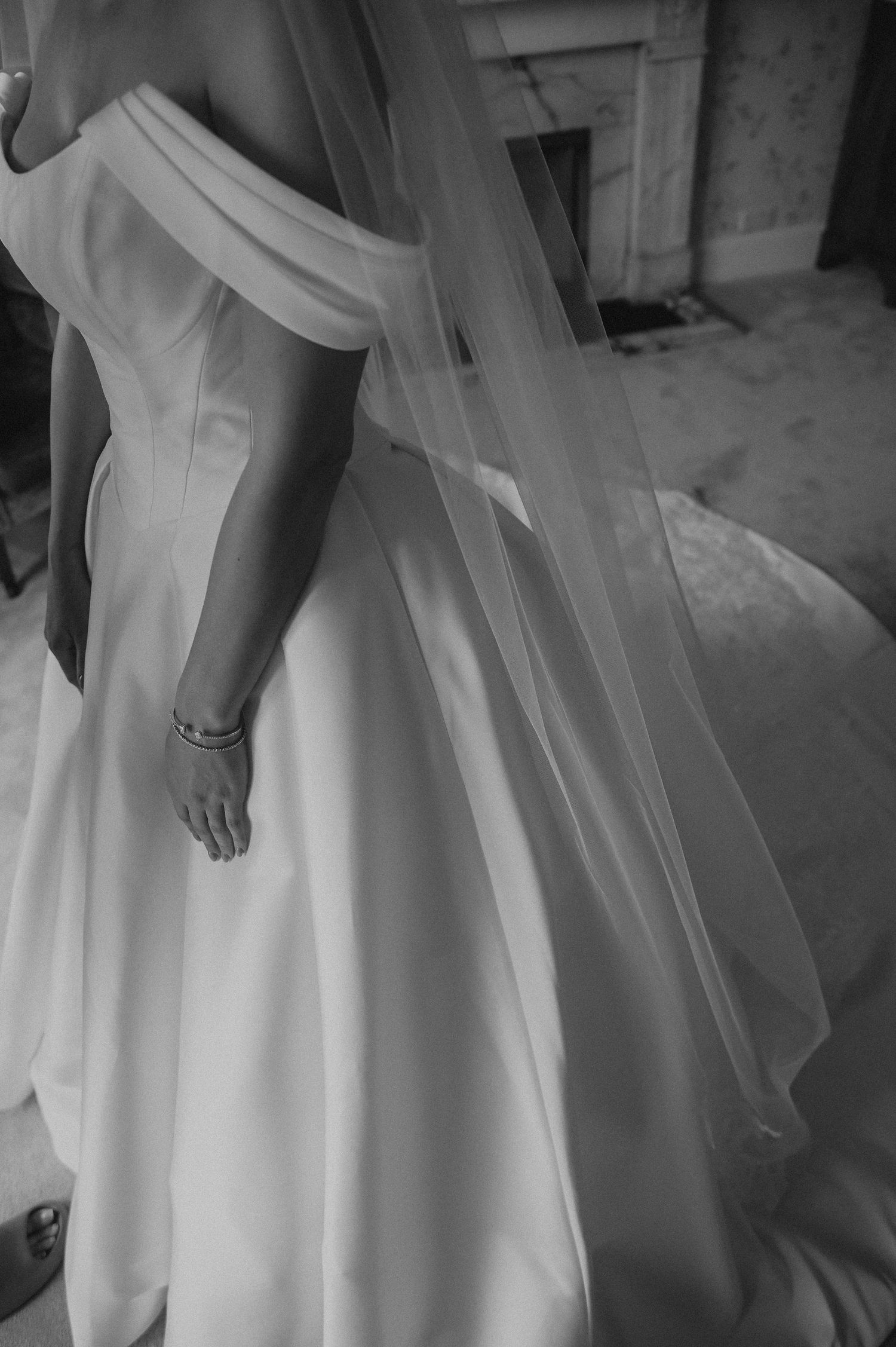 Black and white photograph showing the delicate draping of a wedding dress and veil.