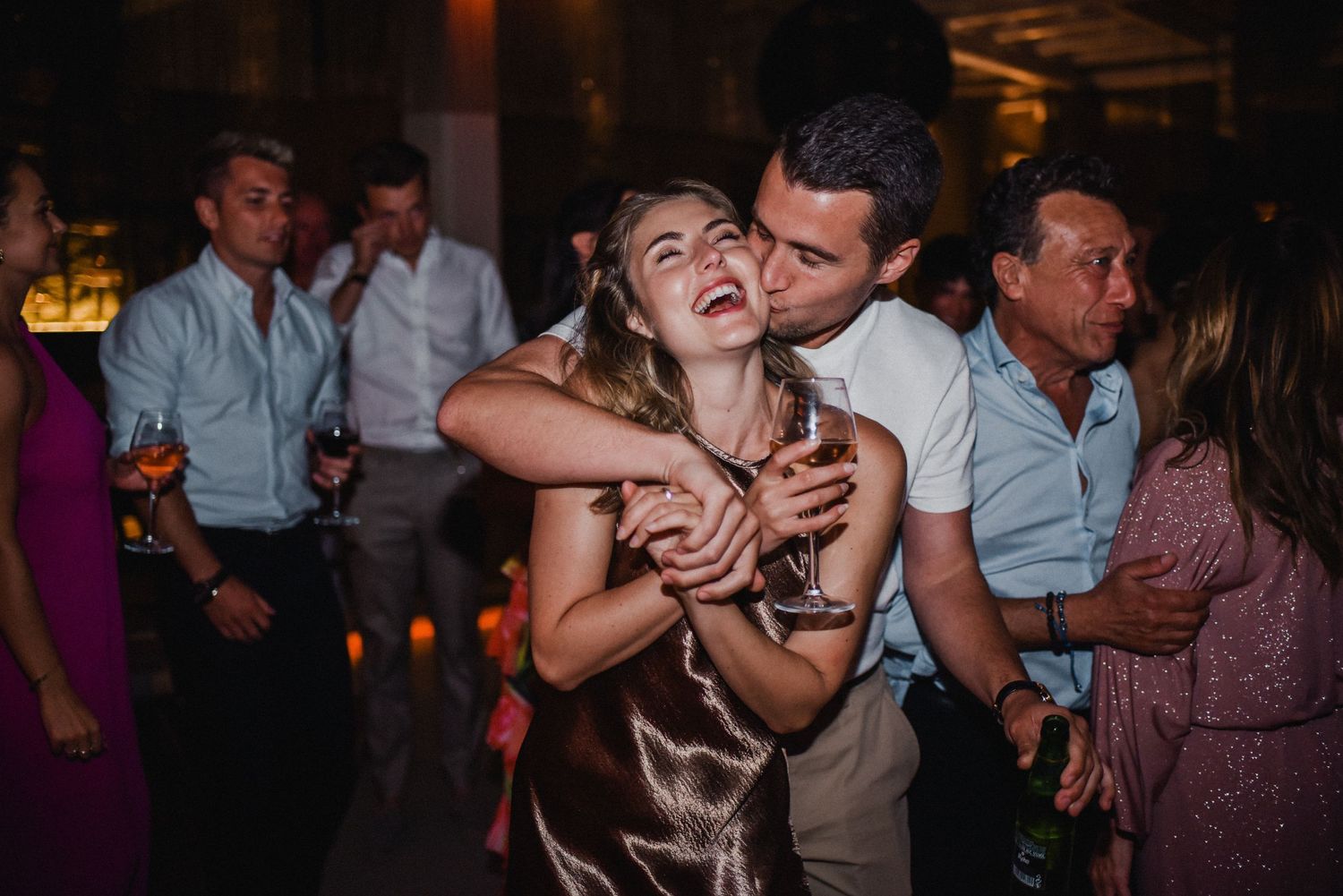 Couples dancing at dimly lit wedding reception party.
