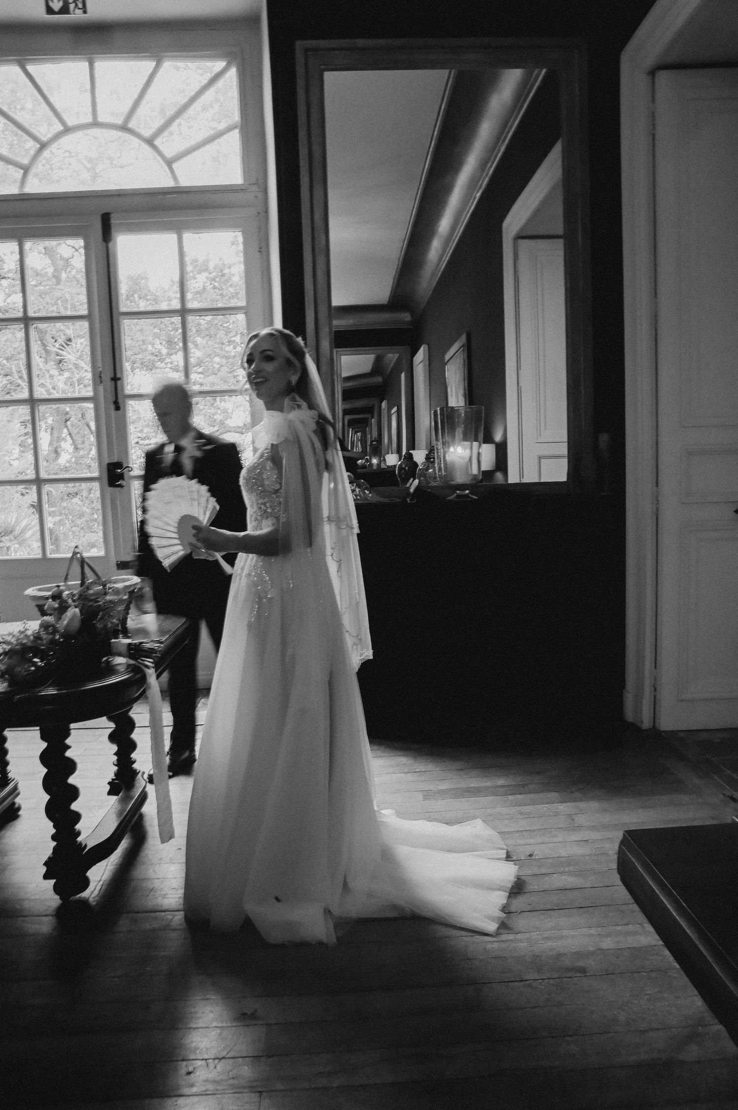 Black and white wedding portrait in an elegant hallway with large windows.