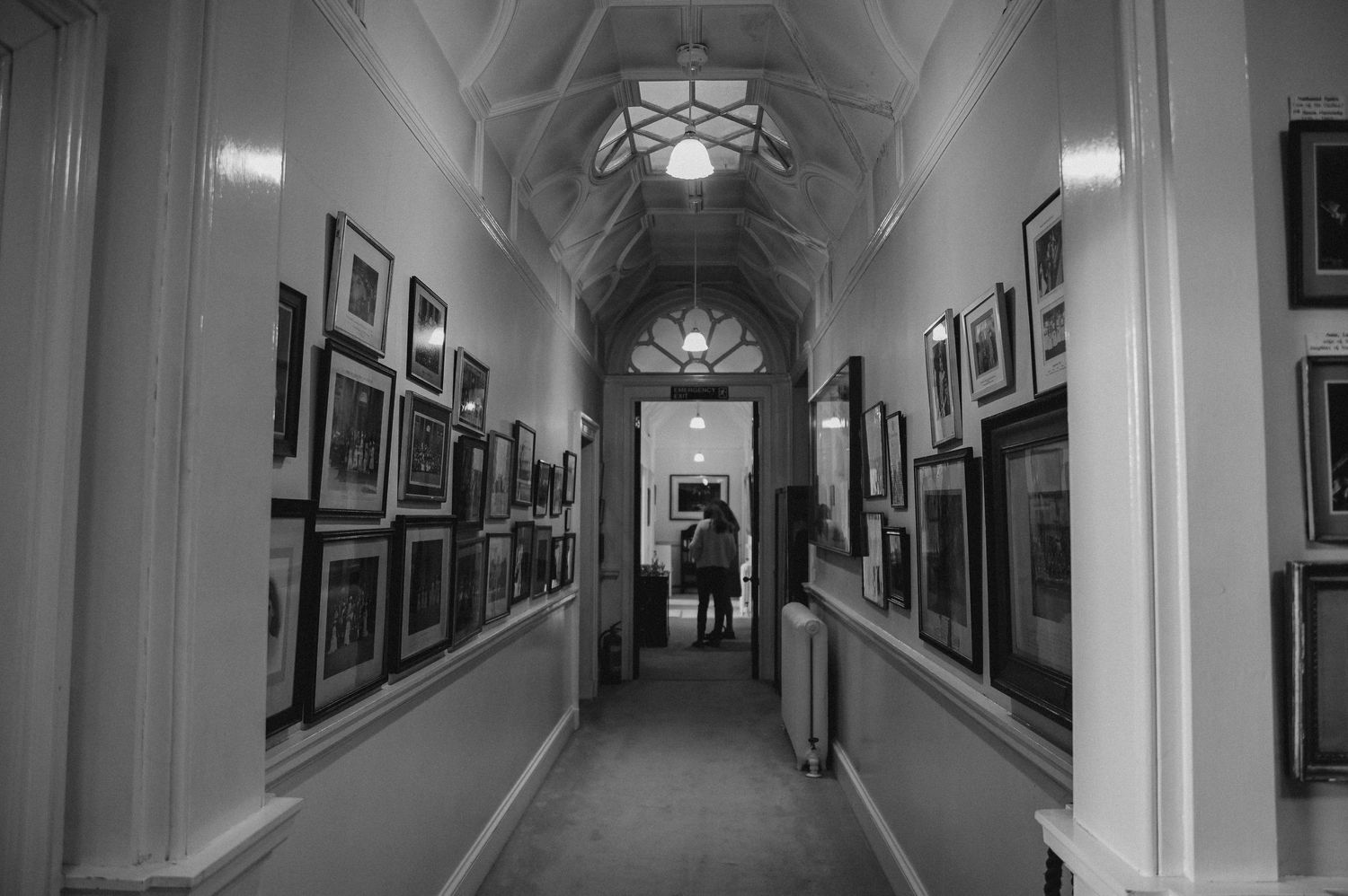 Long gallery hallway with vaulted ceiling and framed artwork lining both walls.