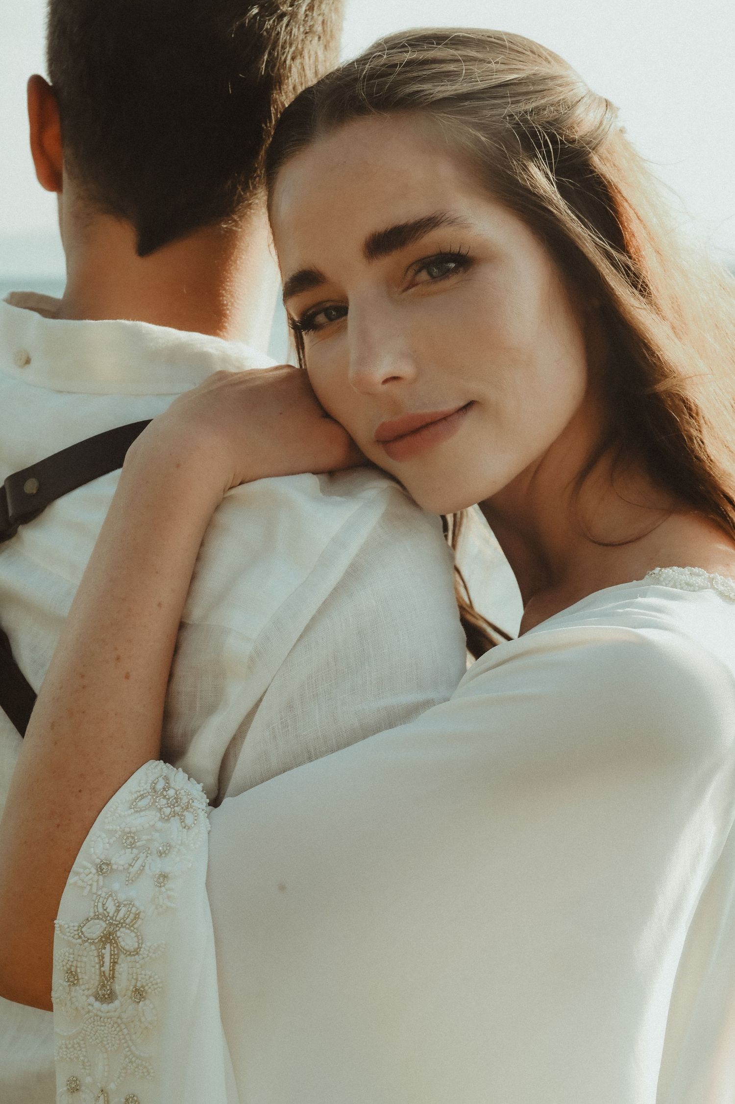 Close-up portrait of bride in natural sunlight with soft romantic ambiance.