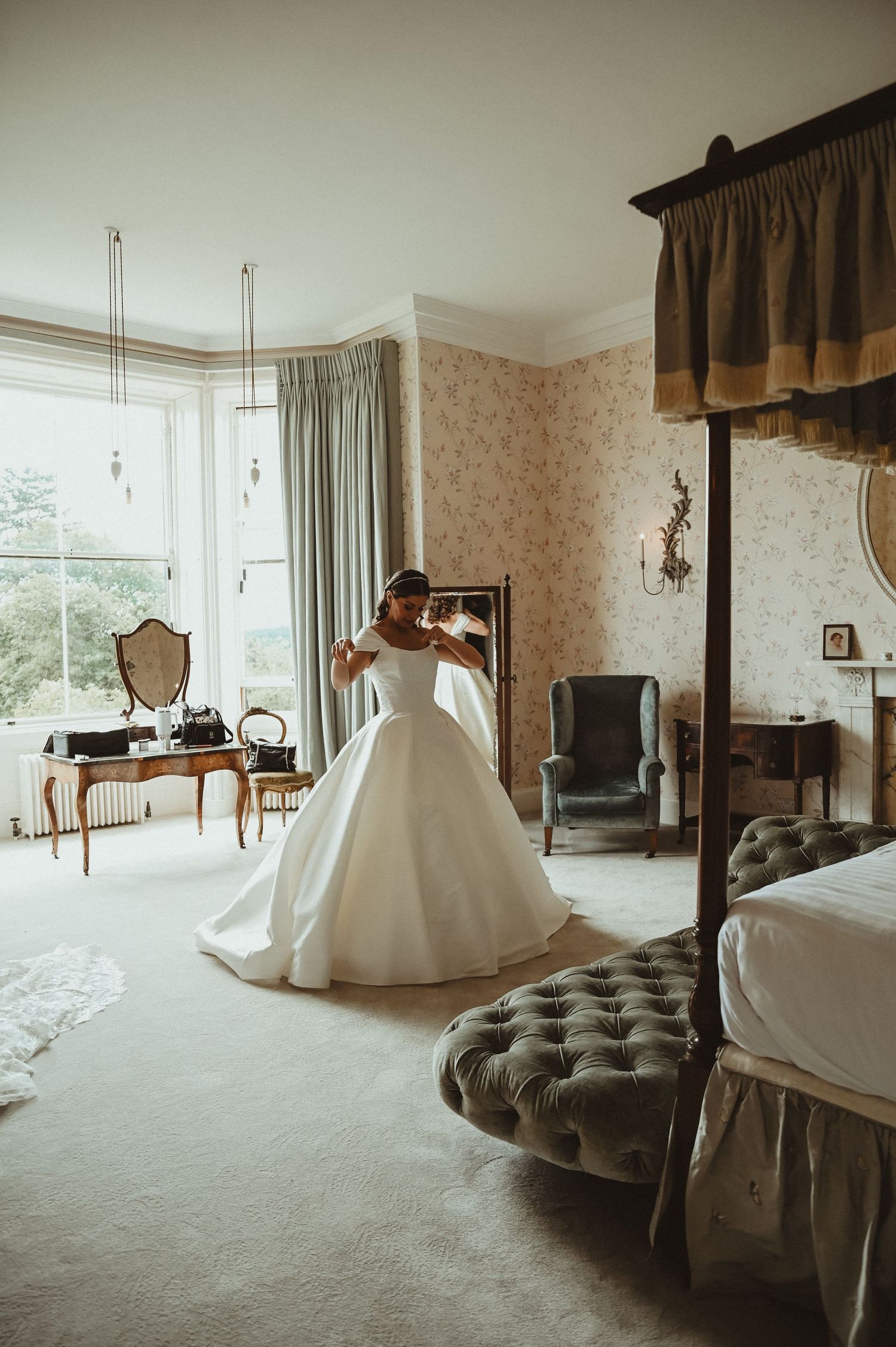 An elegant wedding gown with a full skirt is captured in a vintage-style room with floral wallpaper and classic furniture.