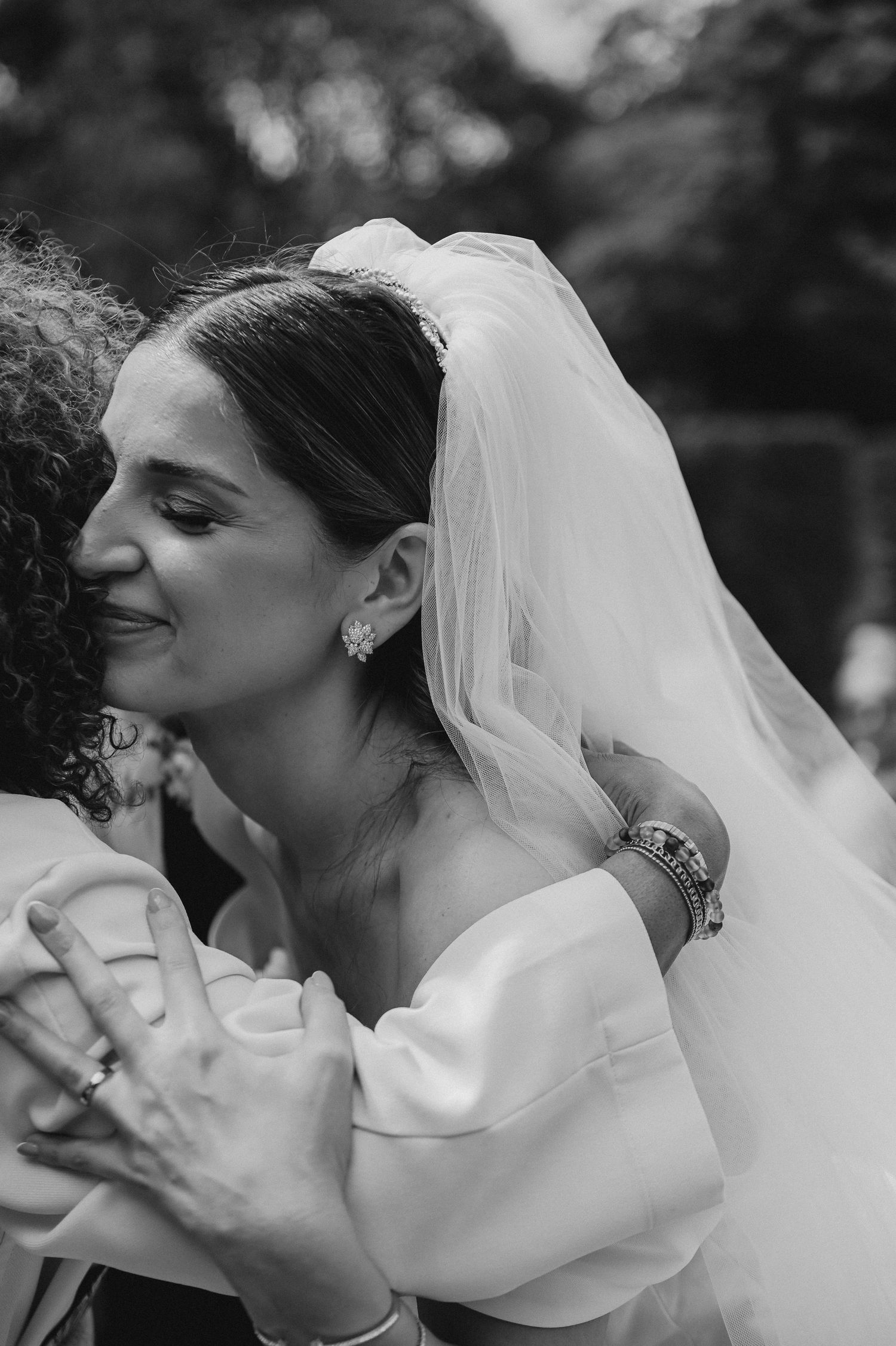 Close-up shot of a bride in a white dress and veil at an outdoor wedding celebration.