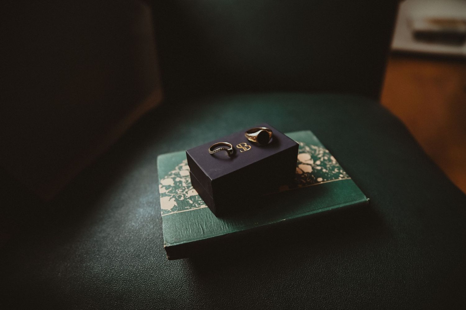 Wedding rings displayed on dark velvet box against green background.