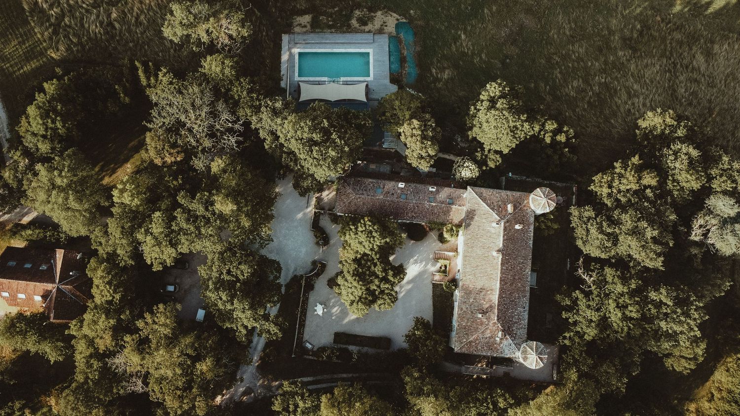 Bird's eye view of a luxury villa with swimming pool surrounded by lush trees.