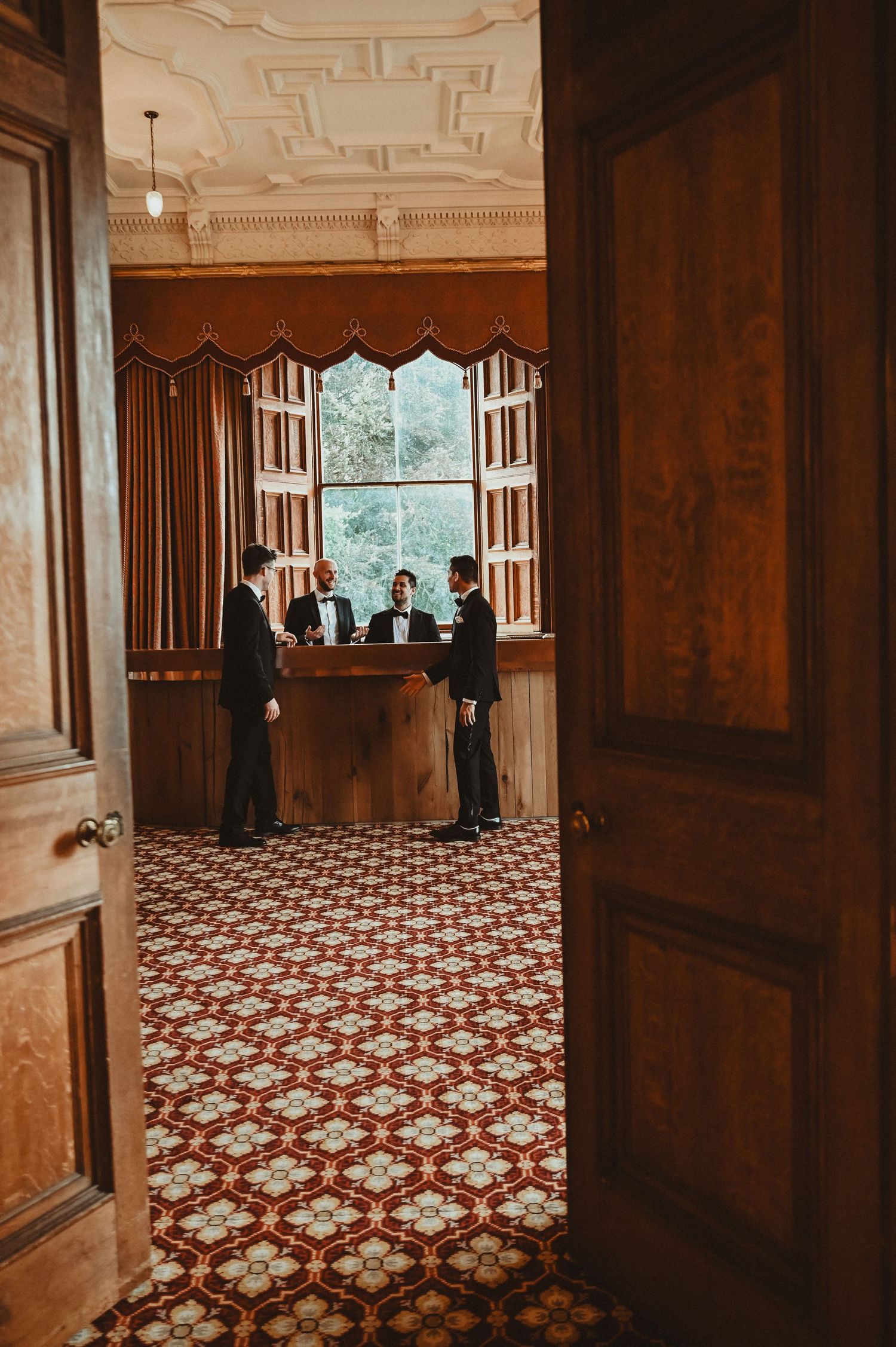 View through doorway of people gathered at a bar in a room with patterned carpet.
