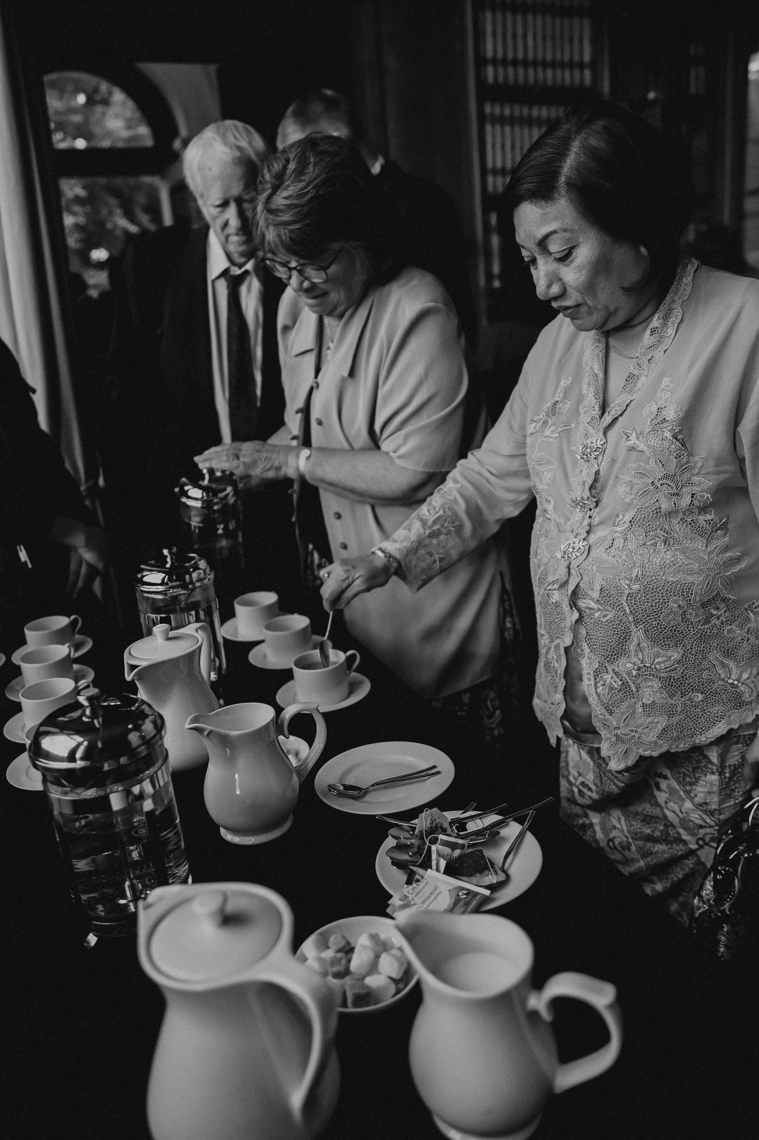 Black and white photo of guests serving coffee and refreshments at an elegant reception.