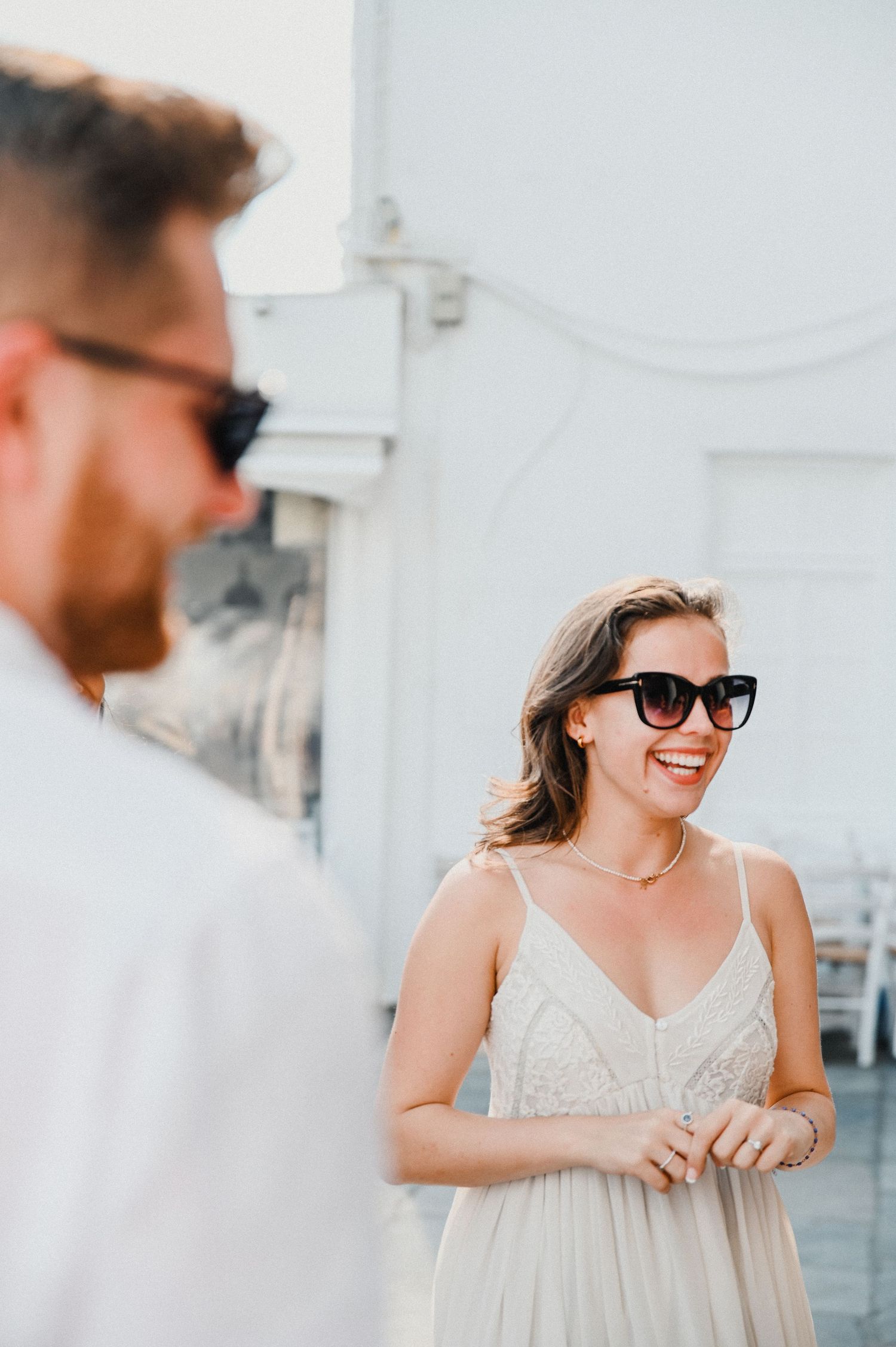 Stylish couple wearing sunglasses share a light moment on a bright summer day.