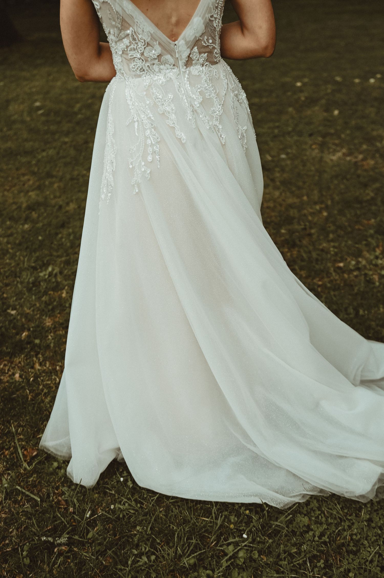 A detailed view of a wedding dress train featuring intricate lace embellishments and flowing tulle fabric.