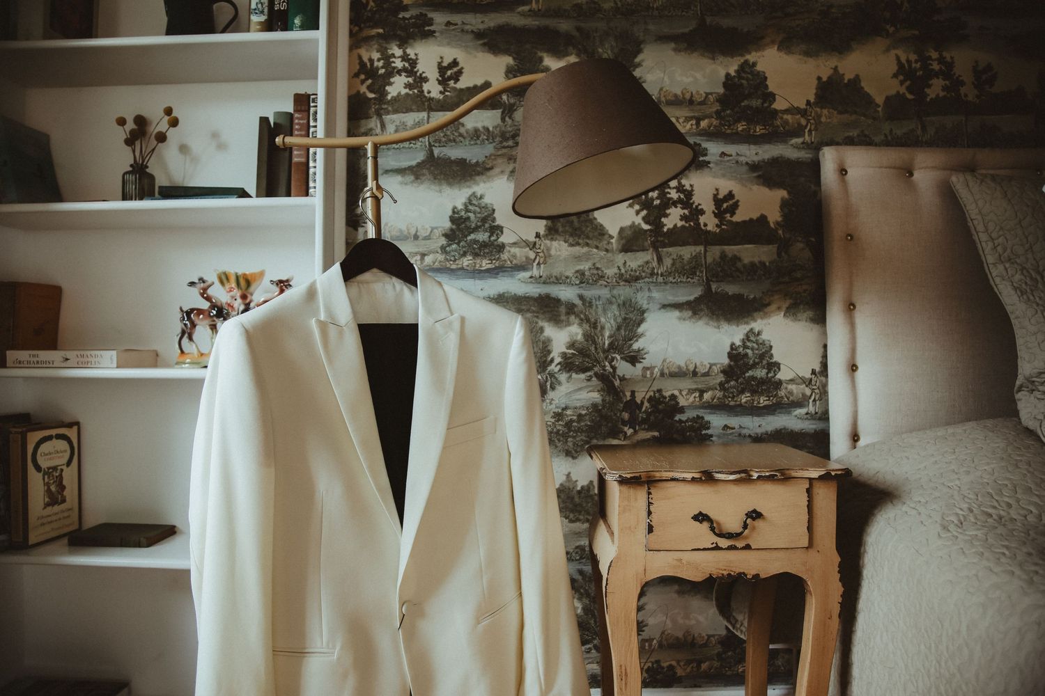 White formal jacket displayed against vintage wallpaper and antique furniture.