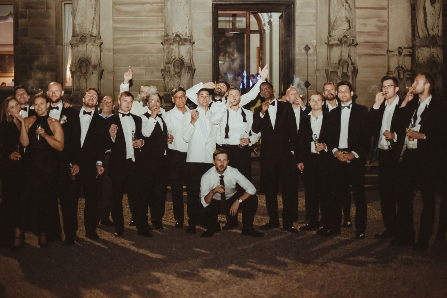 Large group of formally dressed guests celebrate at an elegant indoor venue.