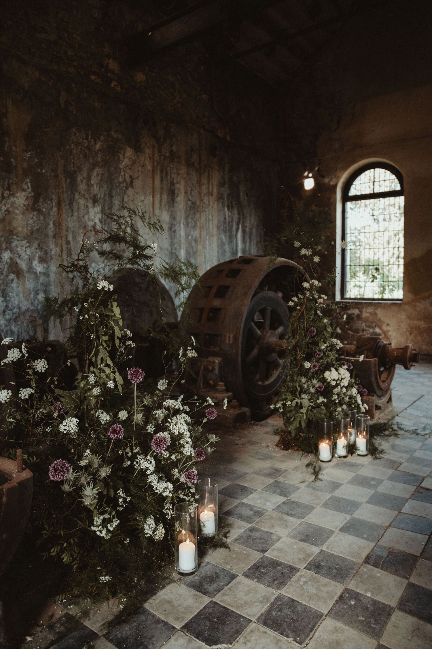 Industrial venue with rustic wheel decorations, flowers and candles on checkered floor.