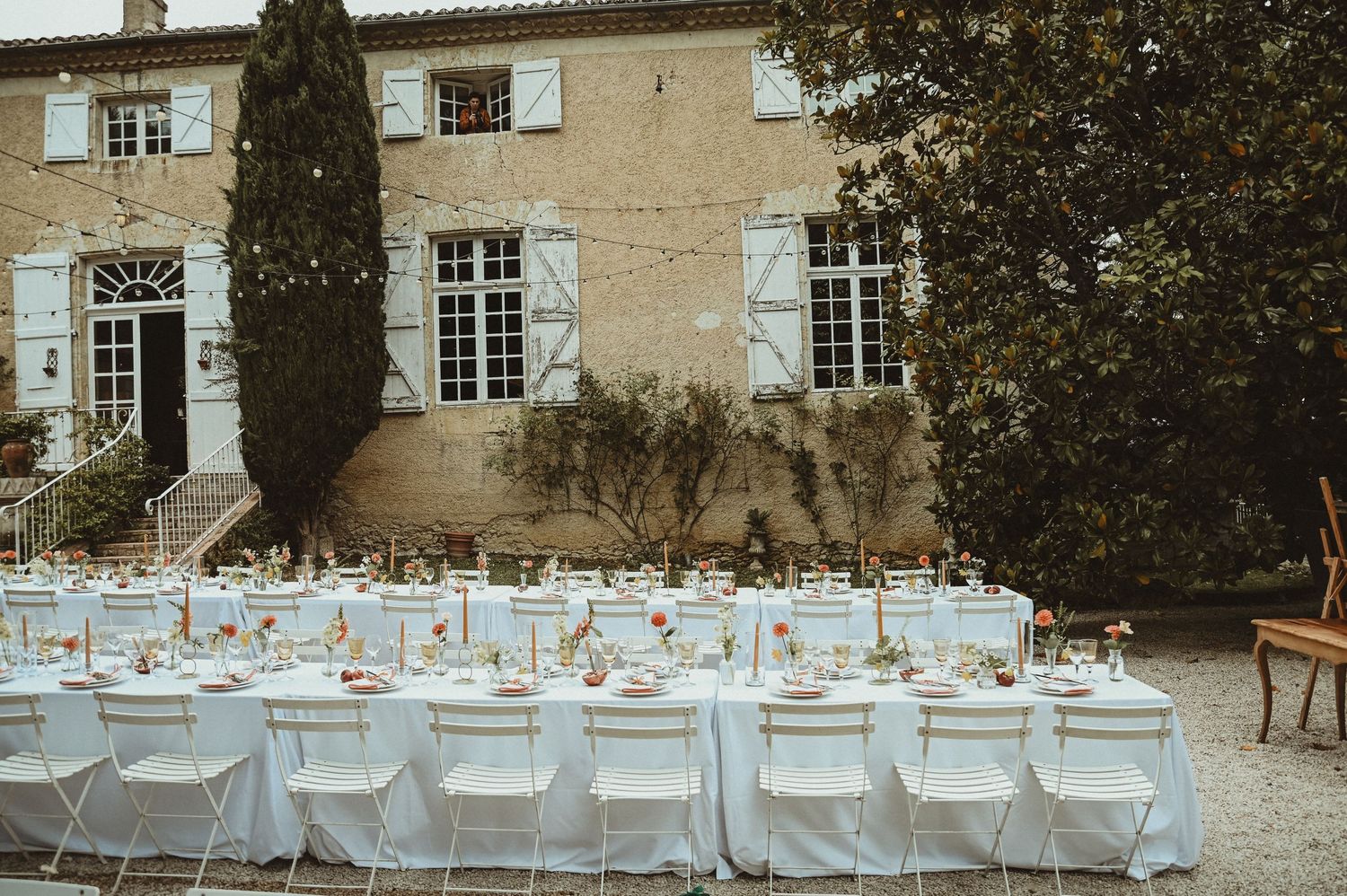 Elegant outdoor wedding reception setup with white tables and chairs at a French chateau.