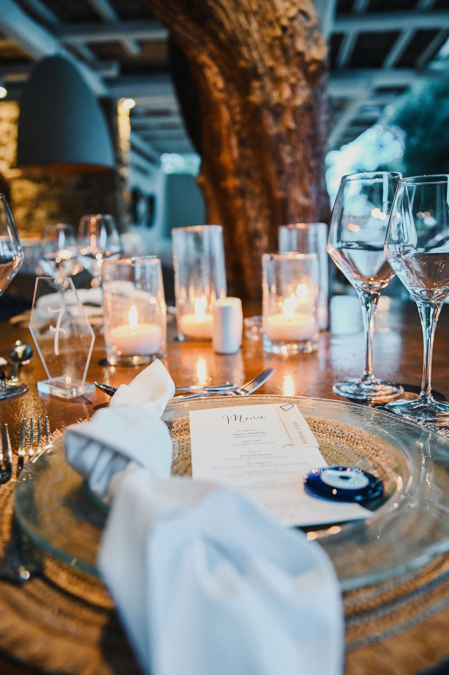 Elegant table setting with wine glasses, candles and menu card in atmospheric restaurant lighting.