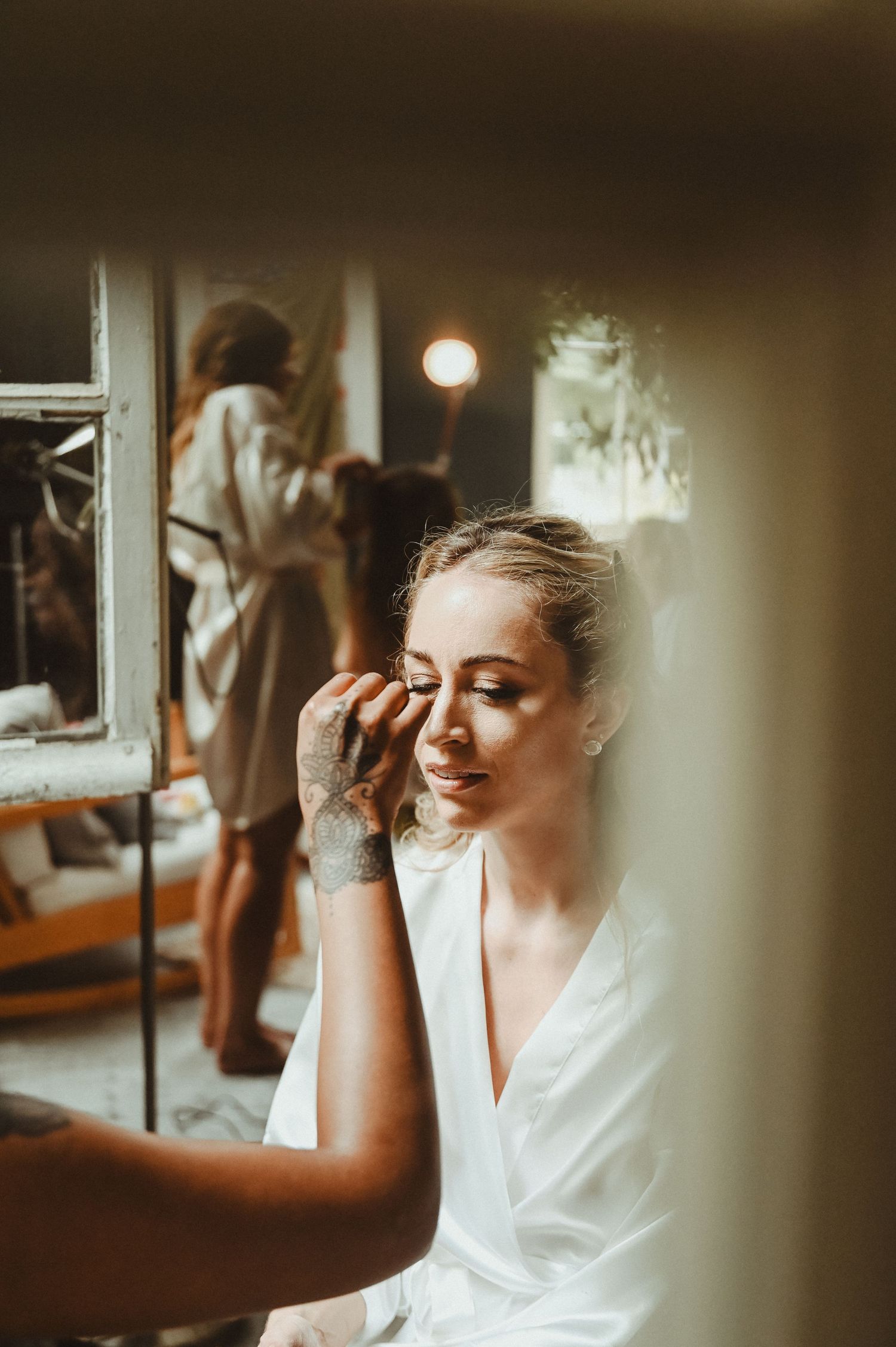 Getting ready scene with someone applying makeup in soft, warm lighting.