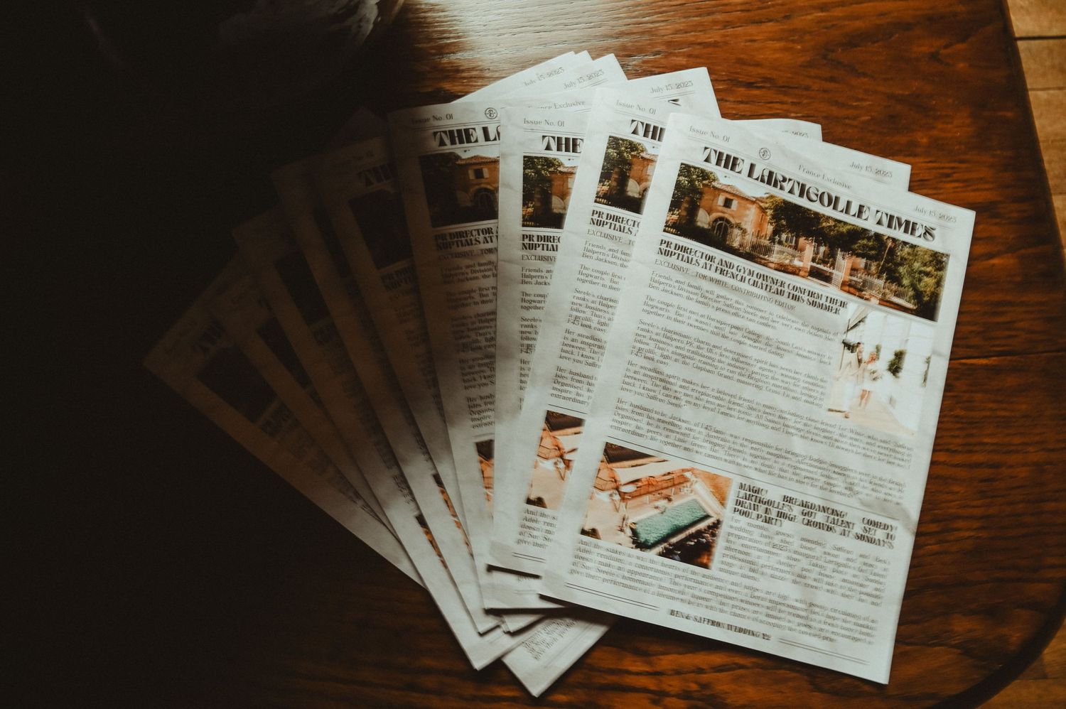 Stack of newspapers laid out on dark wooden table surface.