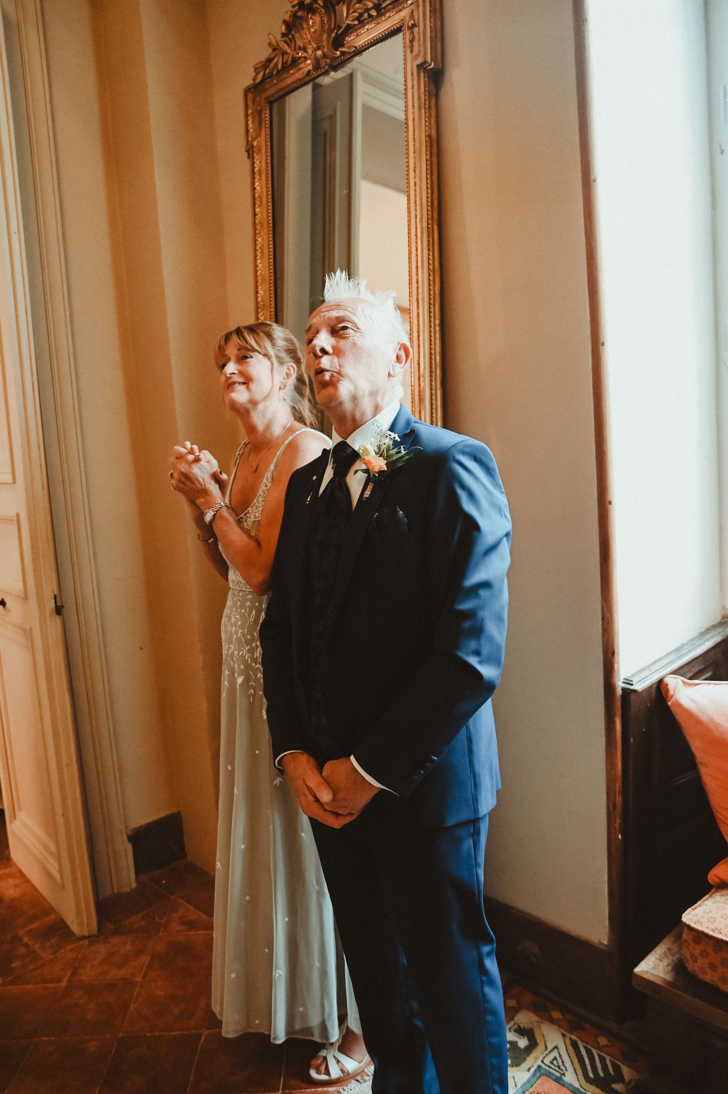 Candid moment captured by an ornate gold mirror in a classic interior setting.
