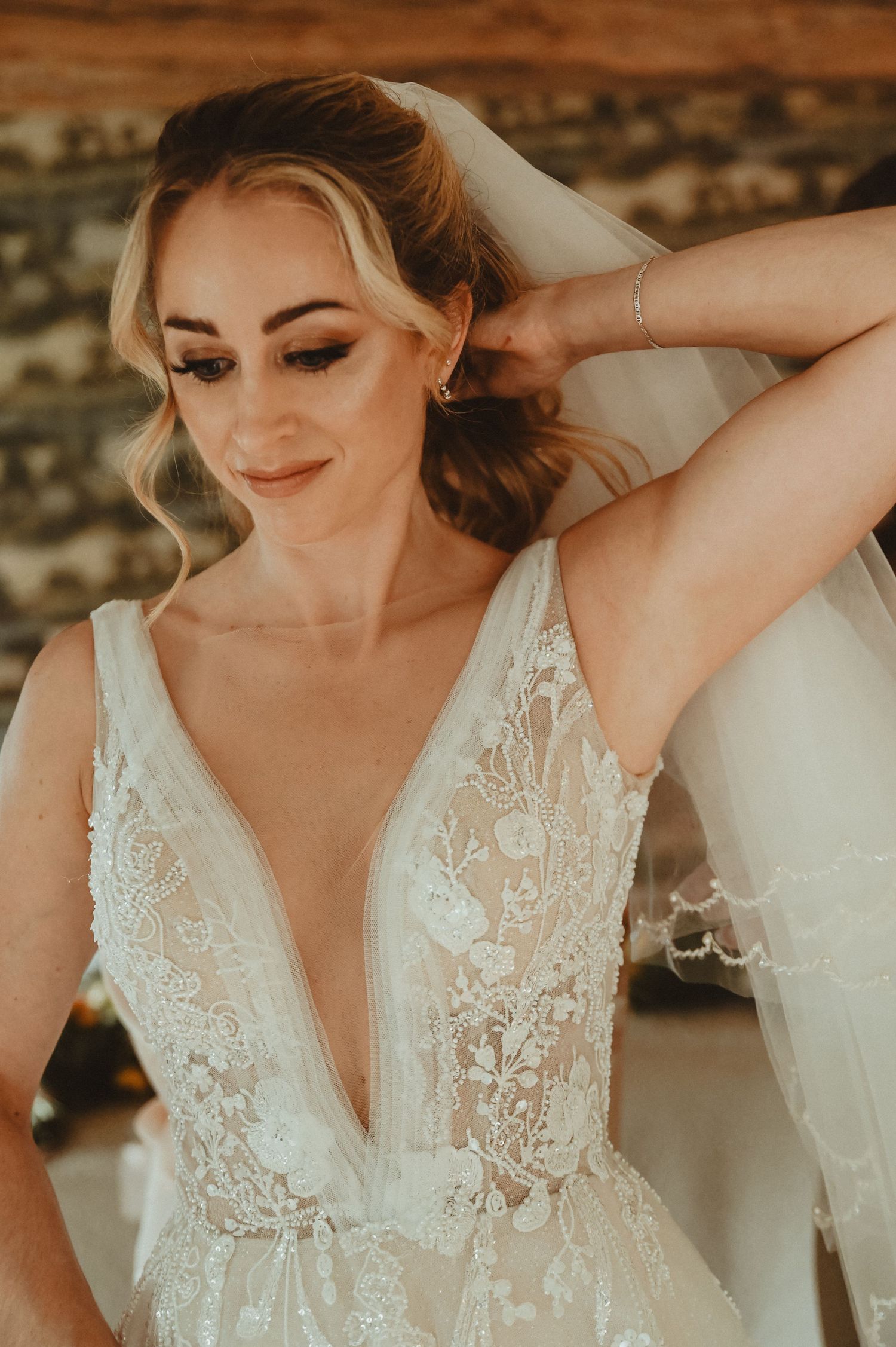 Elegant wedding dress with delicate lace detail and plunging neckline in warm lighting.