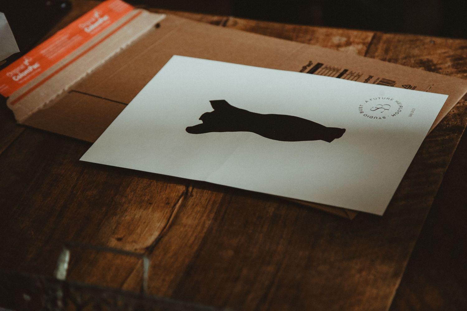 A silhouette illustration of a dog printed on white paper against a wooden surface.