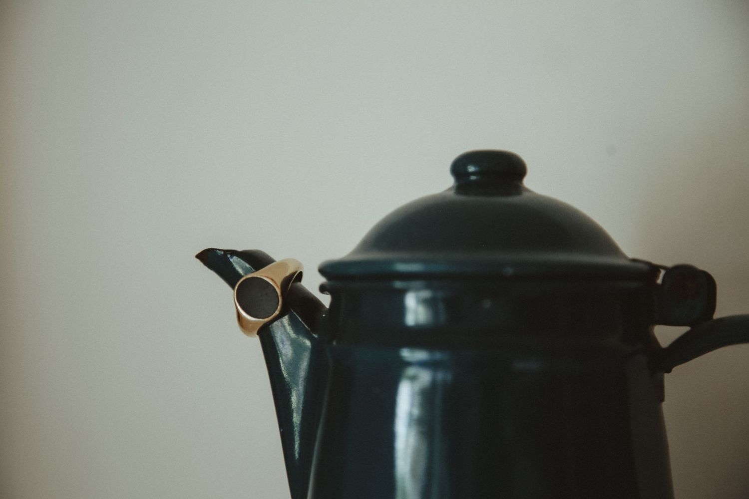 Black vintage teapot photographed against neutral background in moody lighting.