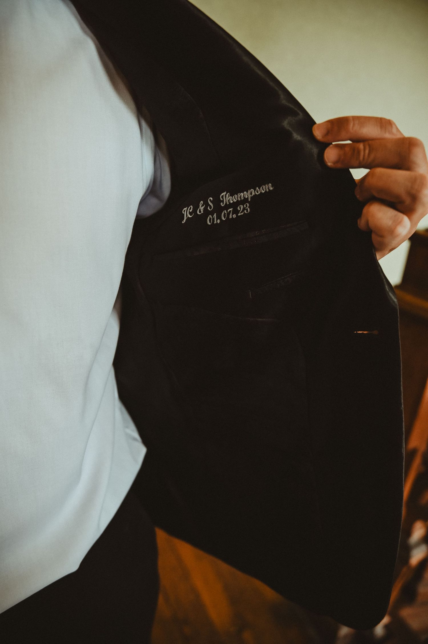 Close-up shot of a monogrammed suit jacket showing personalized embroidered initials.