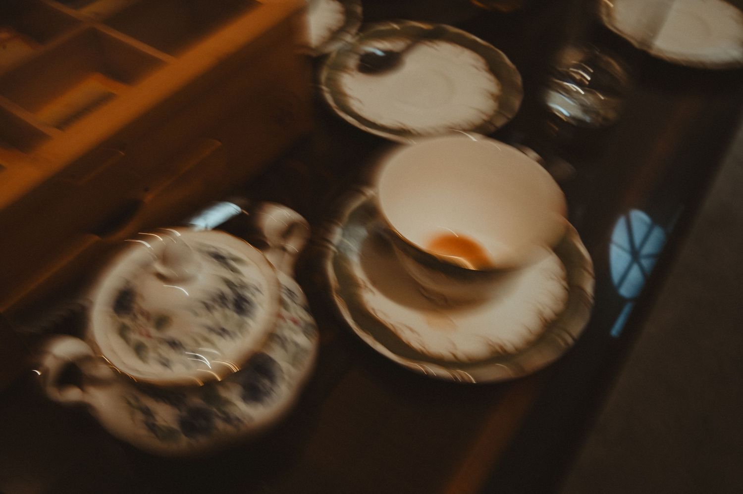 Vintage teacups and saucers arranged on a dark wooden surface in soft focus.