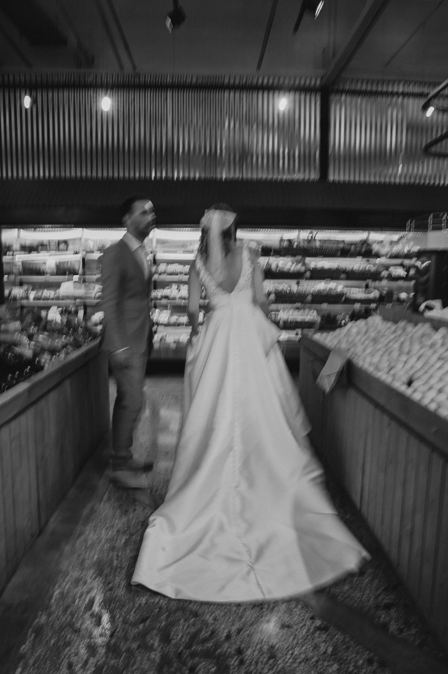 Black and white photo of couple in wedding attire browsing store aisles.