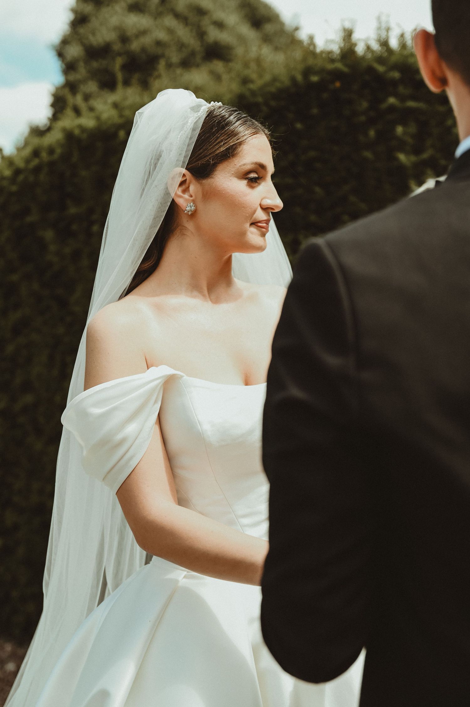 A classic wedding scene with an elegant white bridal gown and veil in an outdoor garden setting.