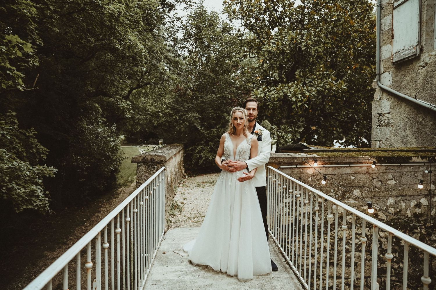A couple shares an intimate moment on a white metal bridge during their wedding.