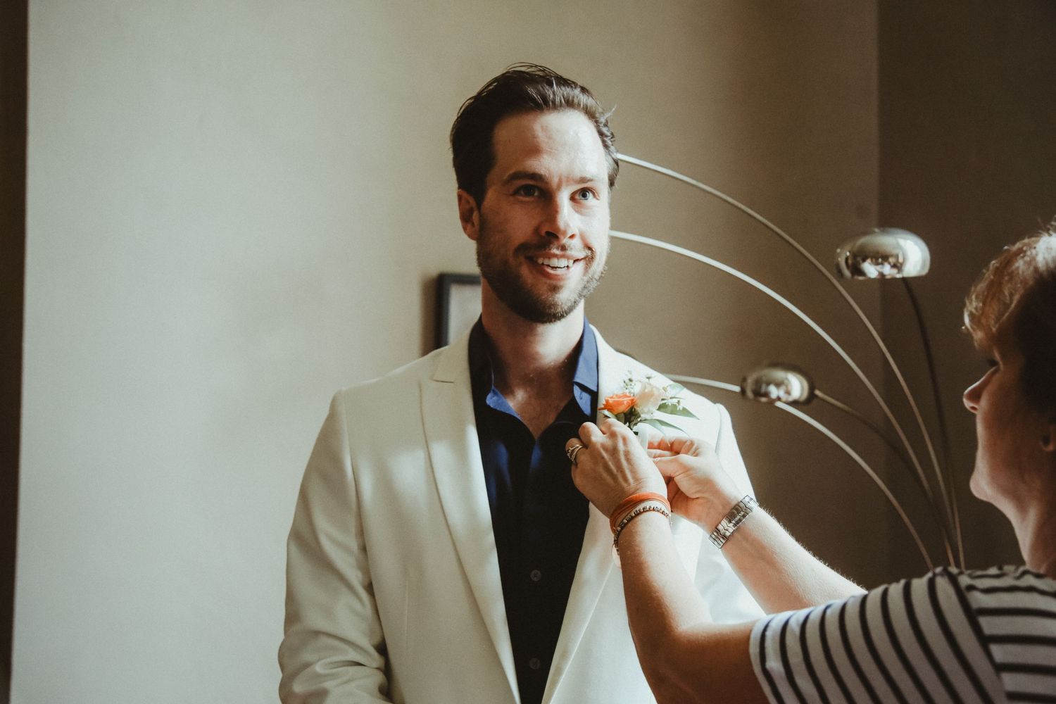 Final preparations being made to a groom's boutonniere before the ceremony.