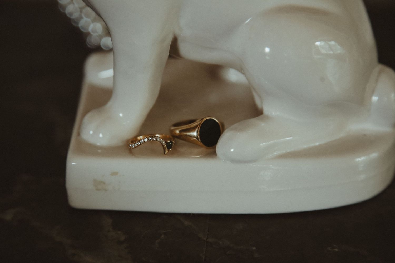 Gold ring with black stone placed near white ceramic figurine.